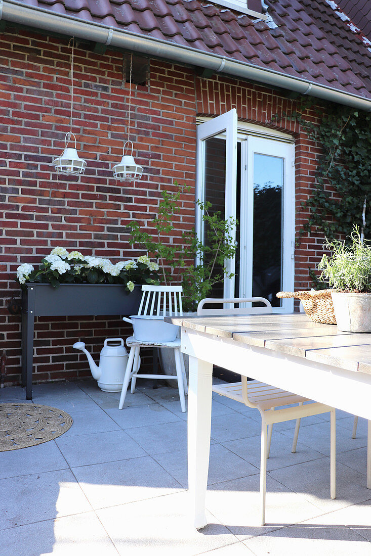 Terrasse mit Hortensien im kleinen Hochbeet an der Hauswand