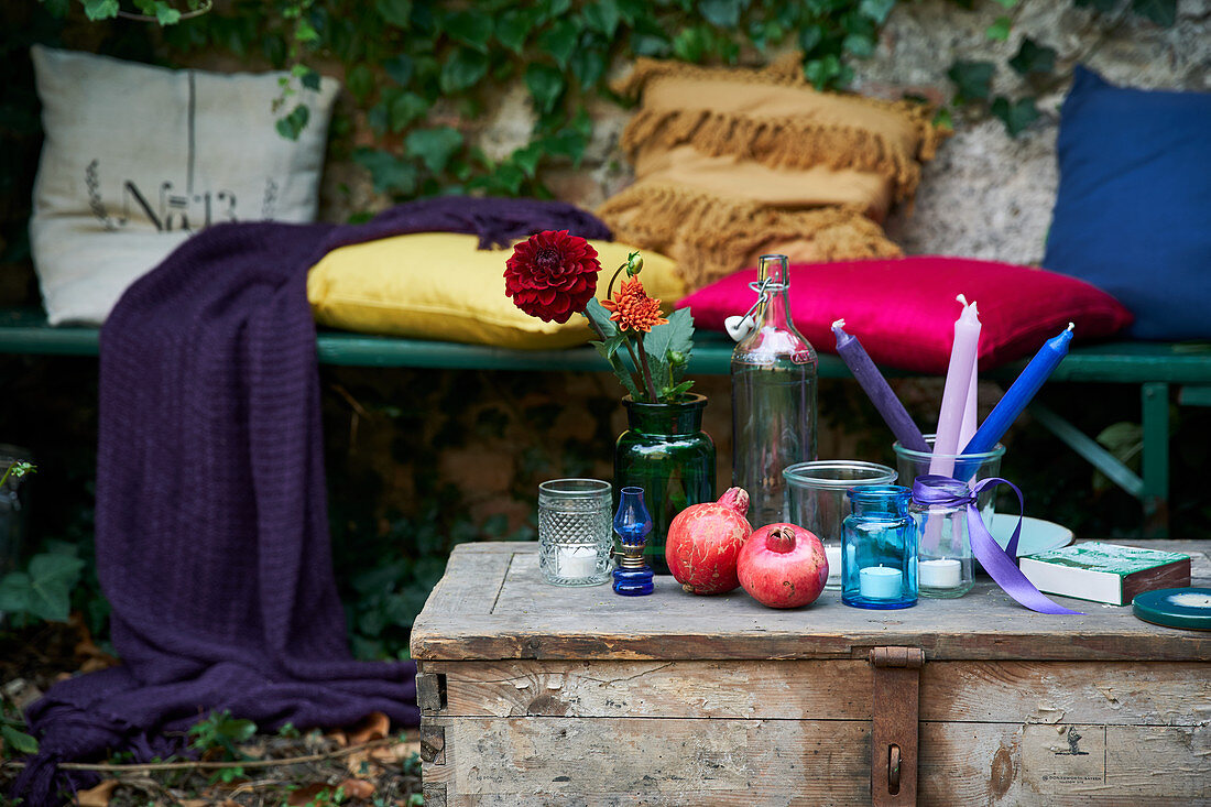 Old wooden trunk used as table and bench with colourful cushions in romantic ivy-covered arbour