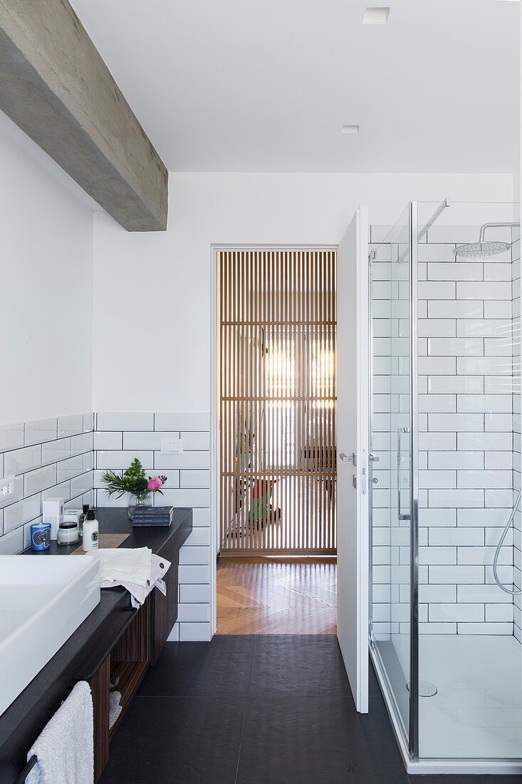 Washstand and glass shower cubicle in bathroom with subway tiles