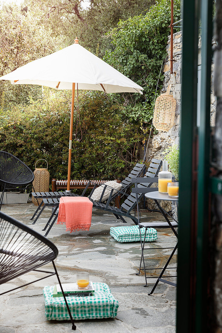 Liegen, Sonnenschirm und Bistrotisch auf der Terrasse mit Natursteinboden