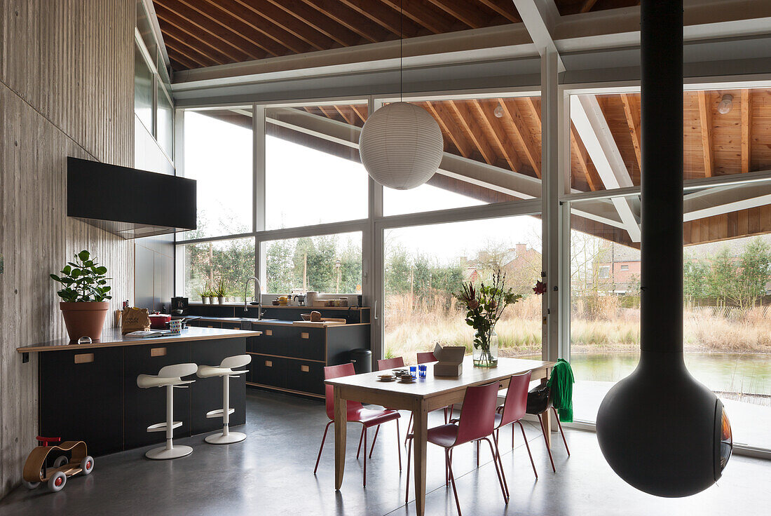 Modern kitchen with dining area, view of the greenery and floating fireplace