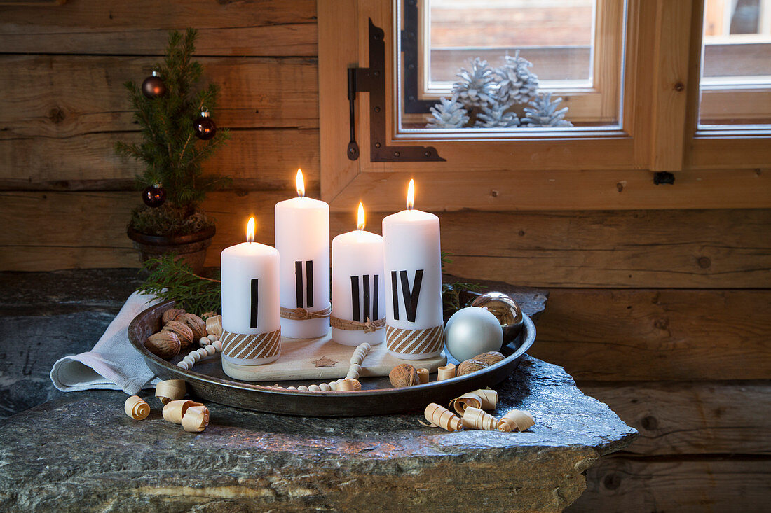 Advent arrangement of candles painted with Roman numerals on tray
