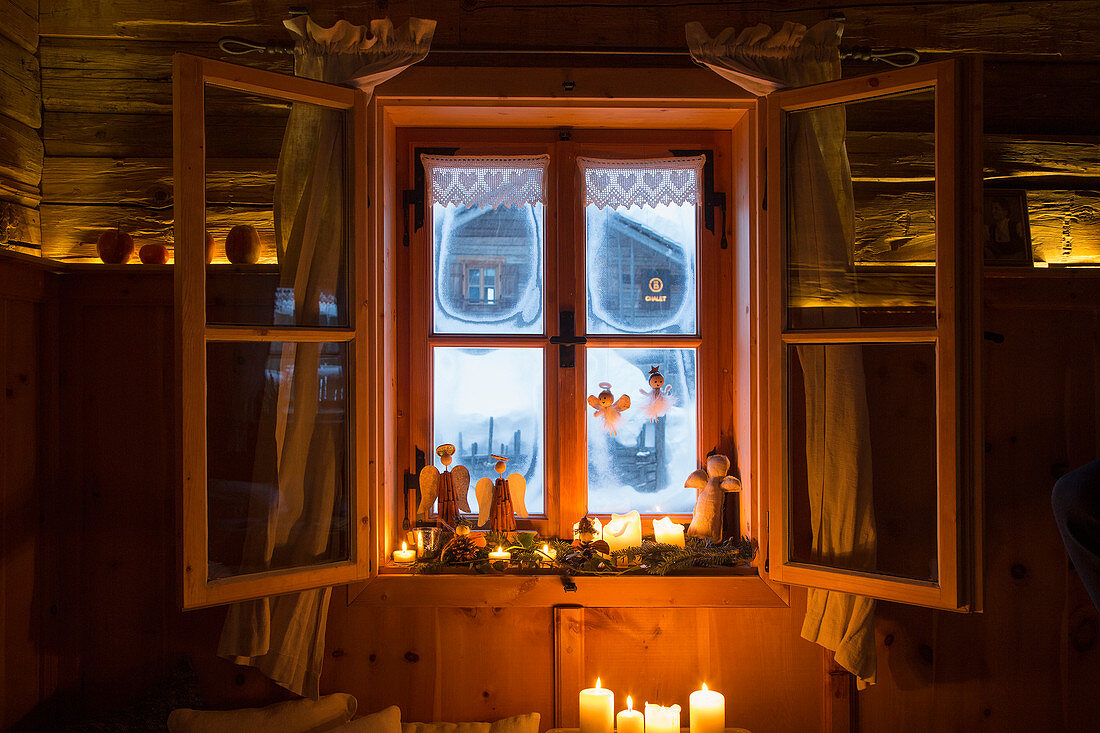 Winterliche Deko mit Engeln und Kerzen am ländlichen Fenster