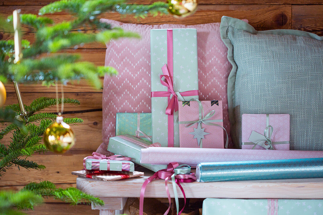 Wrapped gifts and cushions in pink and mint-green on bench
