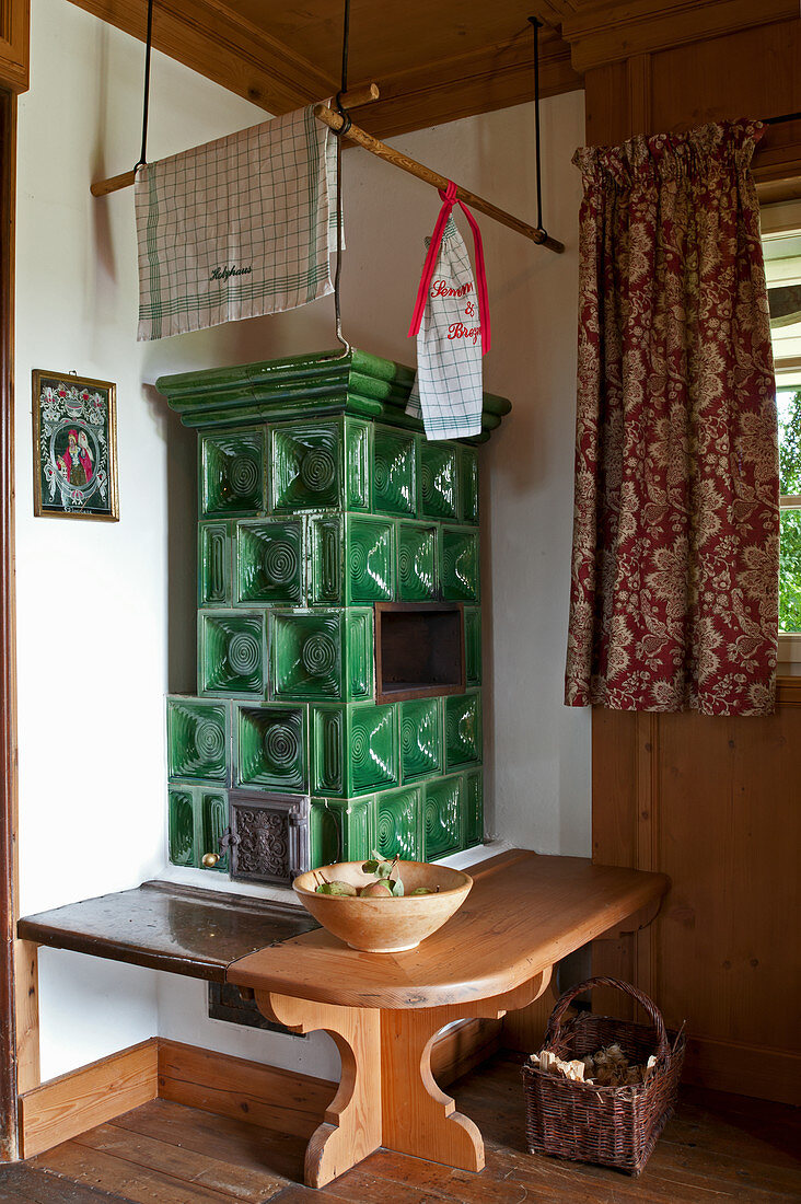 Classic green tiled stove with bench in rustic country house