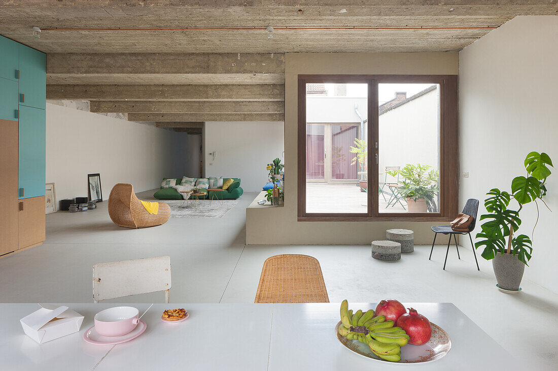 Minimalistisches, offenes Wohnzimmer mit Betondecke und großem Fenster zum Innenhof