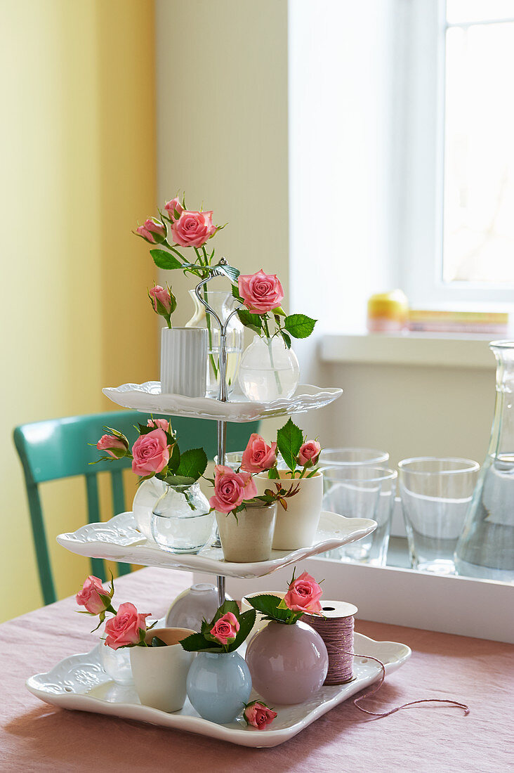 DIY-Etagere dekoriert mit Rosenblüten in kleinen Vasen