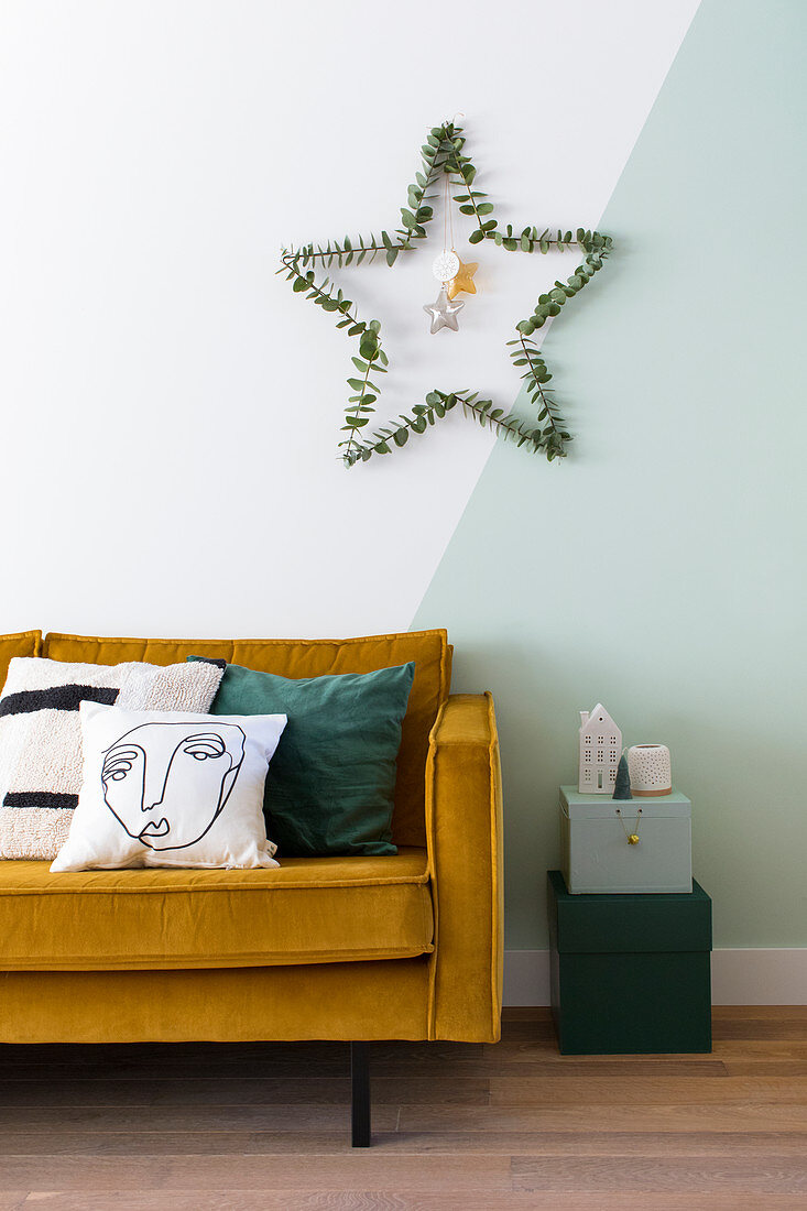 Stern aus Eukalyptuszweigen an zweifarbiger Wand überm Sofa