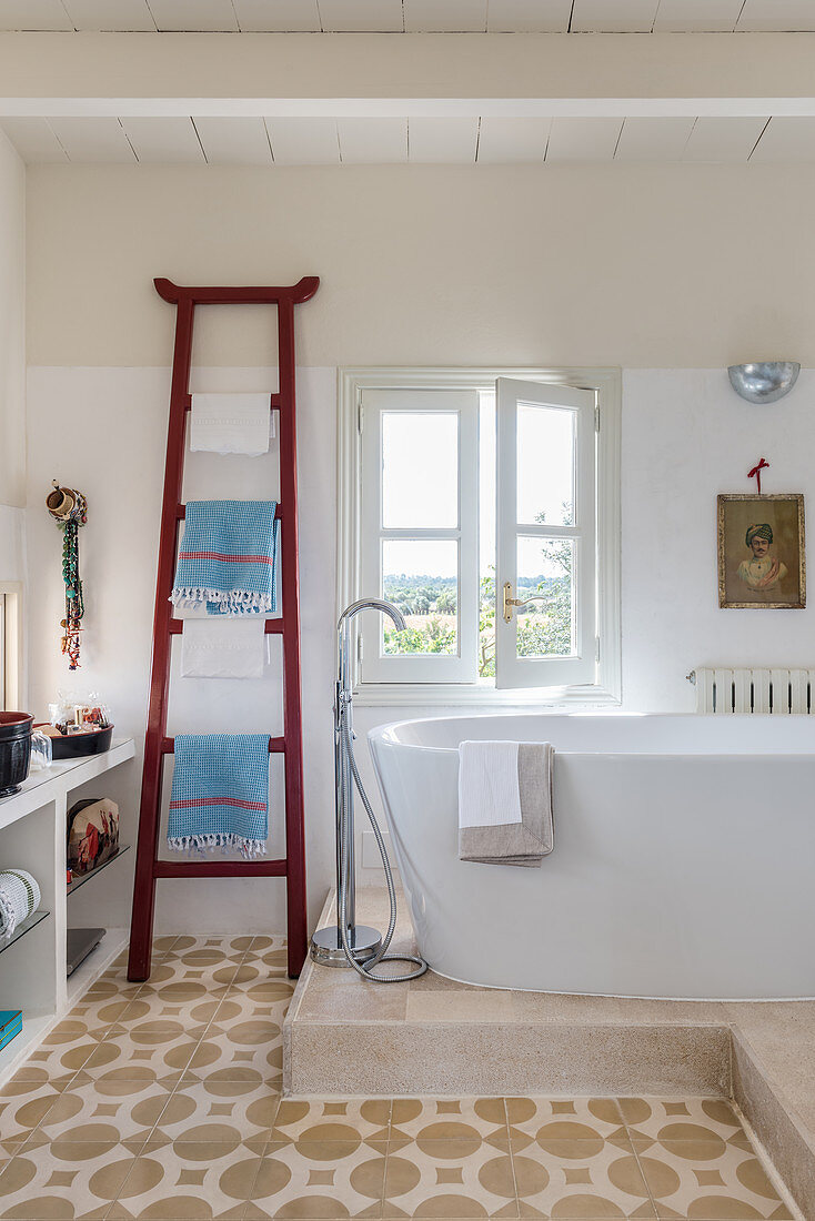 A towel rack next to a freestanding bathtub in an eclectic bathroom