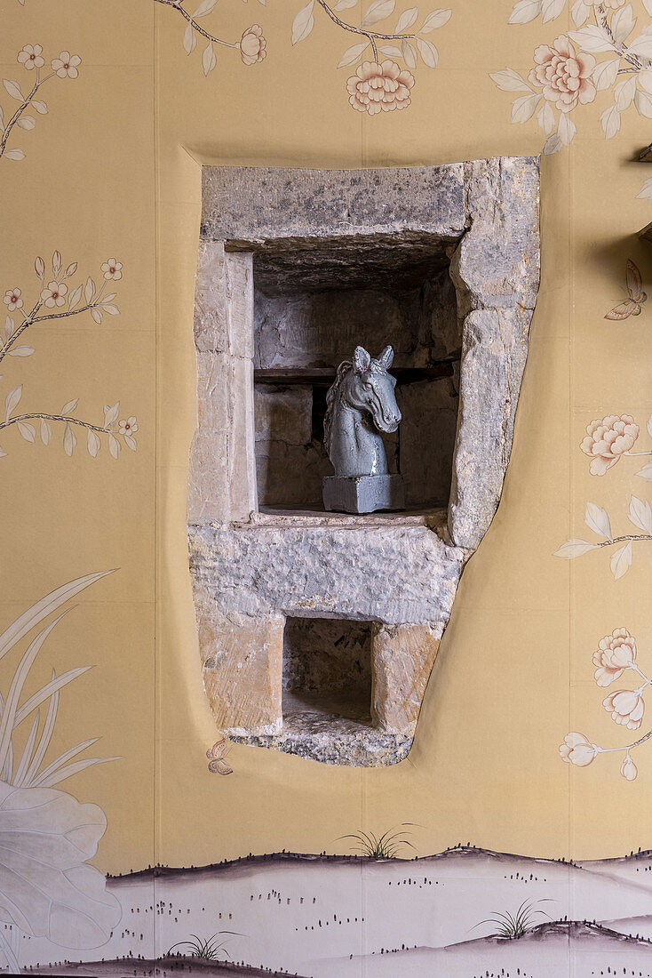 An equestrian statue in a stone niche with 1930s-style wallpaper