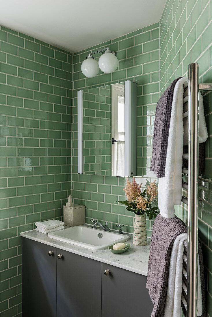 A green tiled bathroom with a wall cabinet