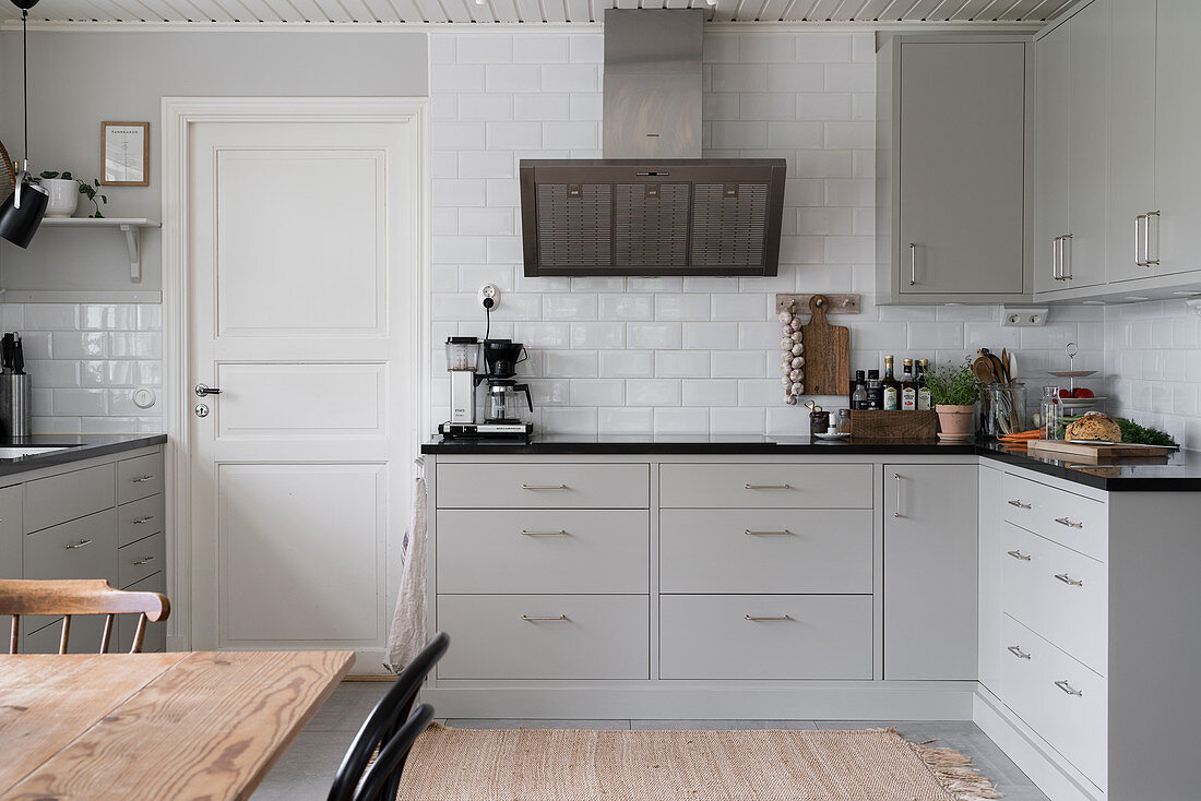 A fitted kitchen with light grey cabinet fronts and subway tiles on the wall