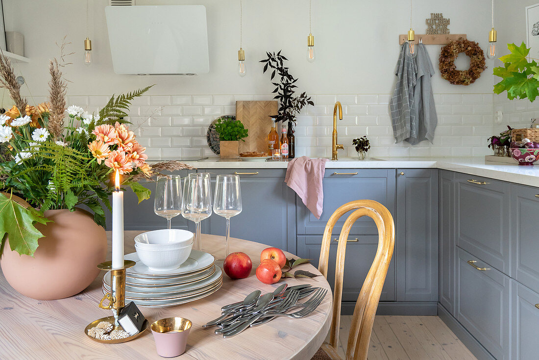 Runder Esstisch aus Holz und Unterschränke mit grauen Fronten in der Küche
