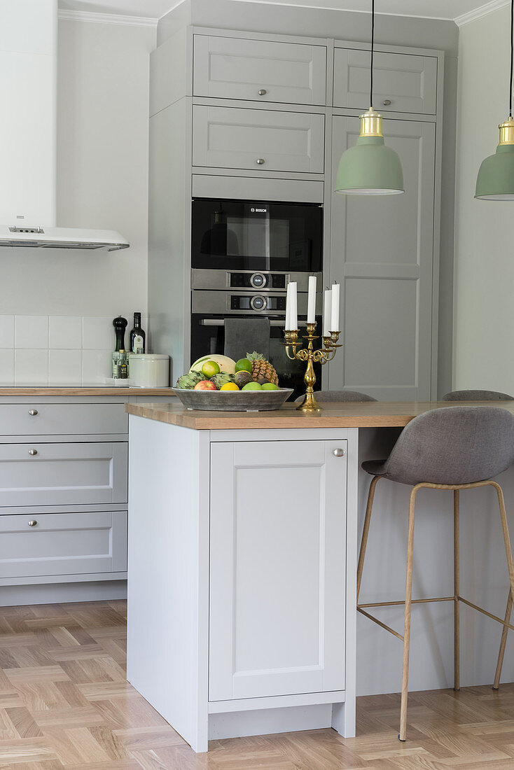 A kitchen with grey cupboard fronts and a breakfast bar with a bar stool