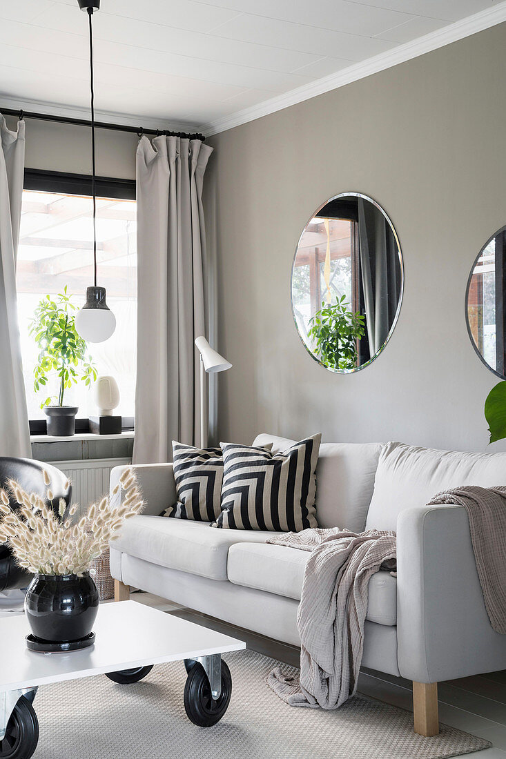 Graues Sofa und Couchtisch auf Rollen im Wohnzimmer mit grauer Wand