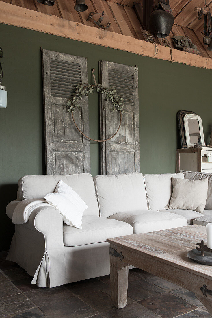 A sofa with a natural white cover in front of vintage doors hanging on a wall