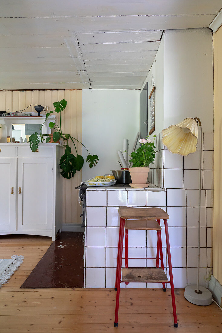 A stool and a floor lamp against a tiled wall in a kitchen