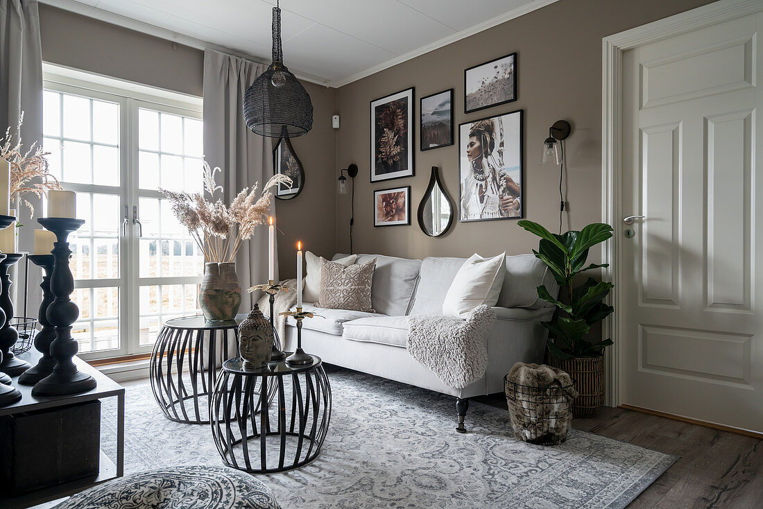 A sofa and coffee tables in a living room with a taupe wall