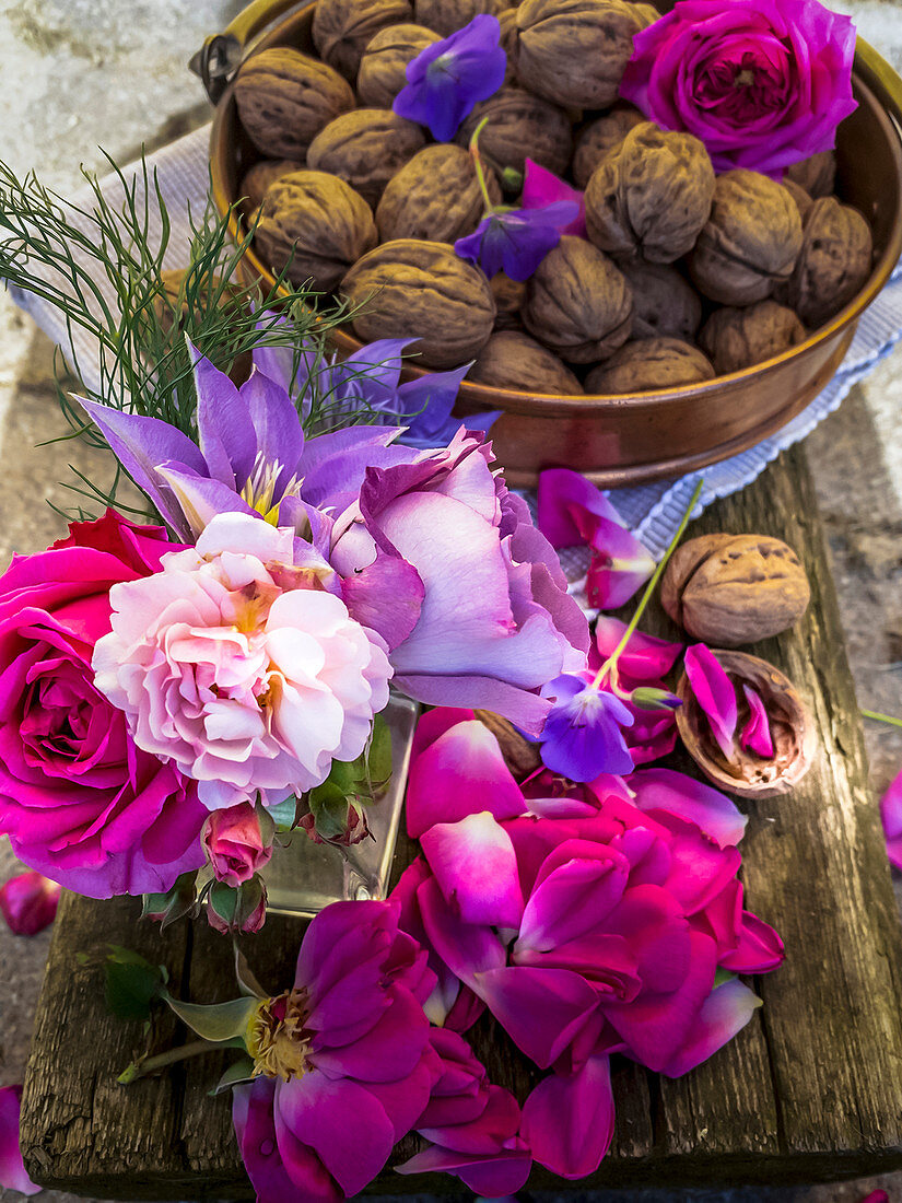 Deko mit Rosenblüten, Storchschnabel, Clematis und Walnüssen
