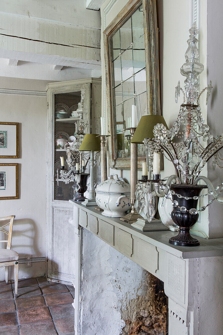 Mantelpiece with candelabra, table lamp and candlesticks below mirror