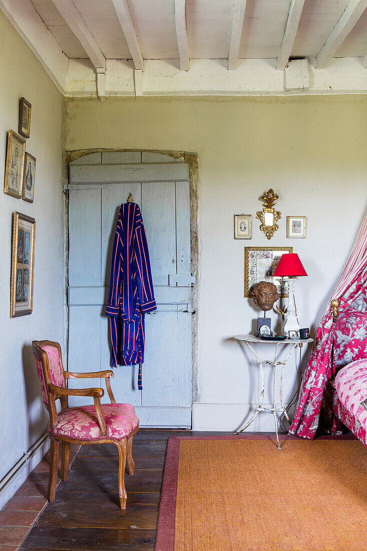 Chair in front of wooden door with bathrobe in bedroom