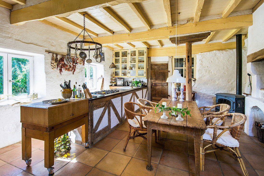 Wooden table with rattan chairs in country kitchen with wooden beamed ceiling