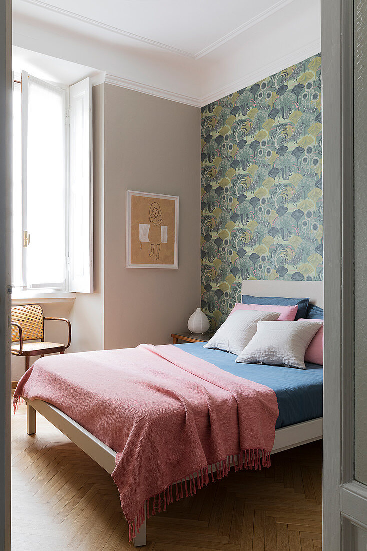 A double bed in a bedroom with wallpaper on a wall