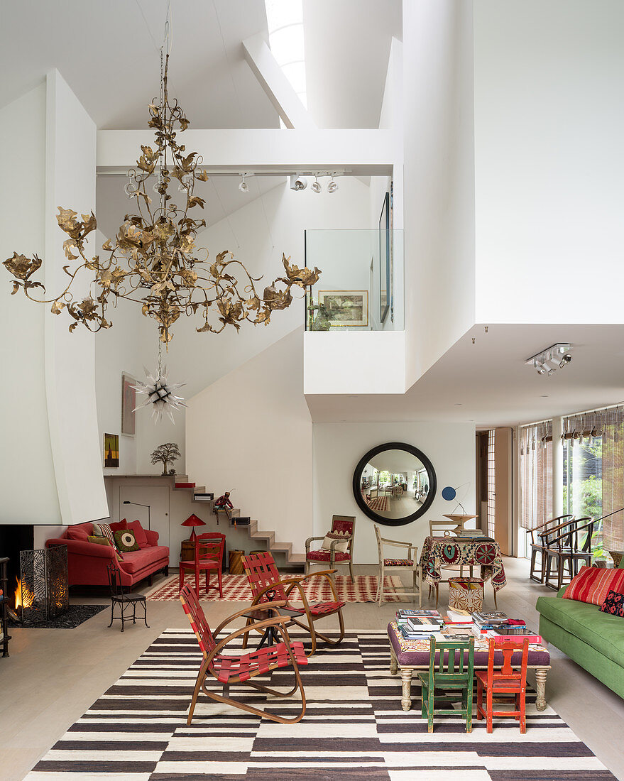 Rote Holz- und Lederstühle und goldener Papierkronleuchter in Wohnraum in dreifacher Raumhöhe