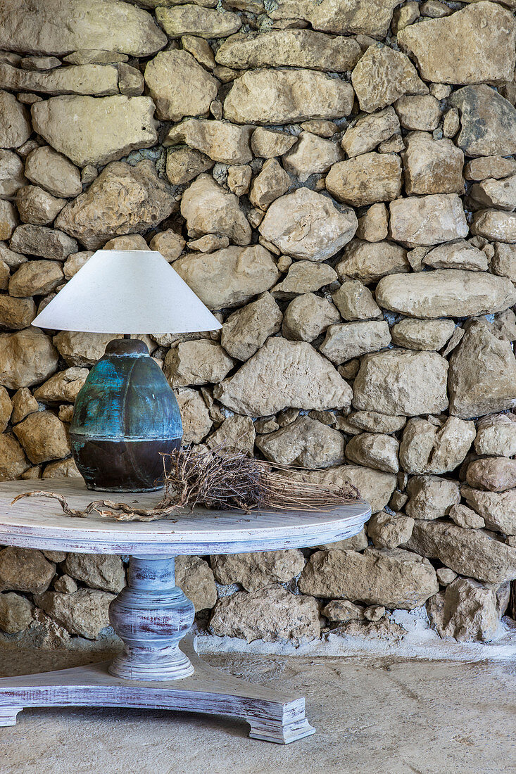 Round table with table lamp against stone wall