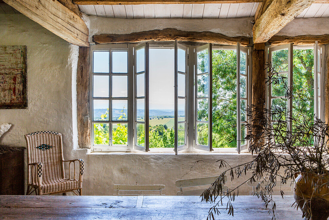 View across dining table to rattan chair and window