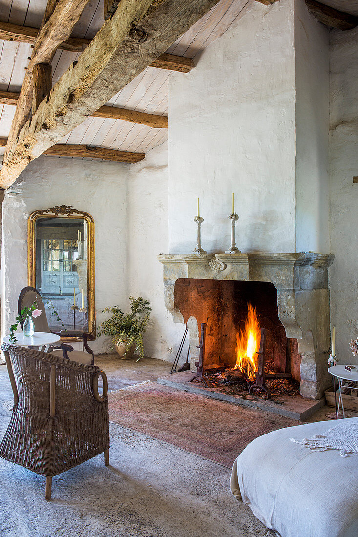 Fire in fireplace in rustic room with wood-beamed ceiling