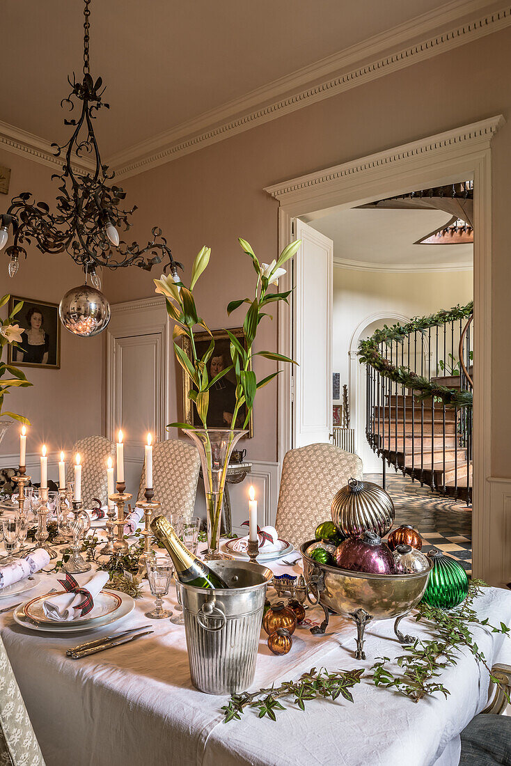 Christmas table festively set with lilies and mercury glass candlesticks below antique copper chandelier