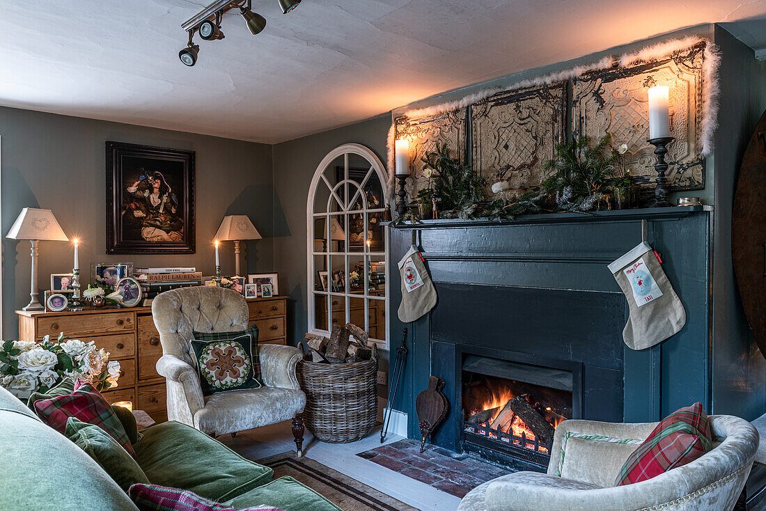 Blauer Kamin mit Weihnachtsdekoration, Rundbogenspiegel, Kommode und Sitzmöbel im Wohnzimmer
