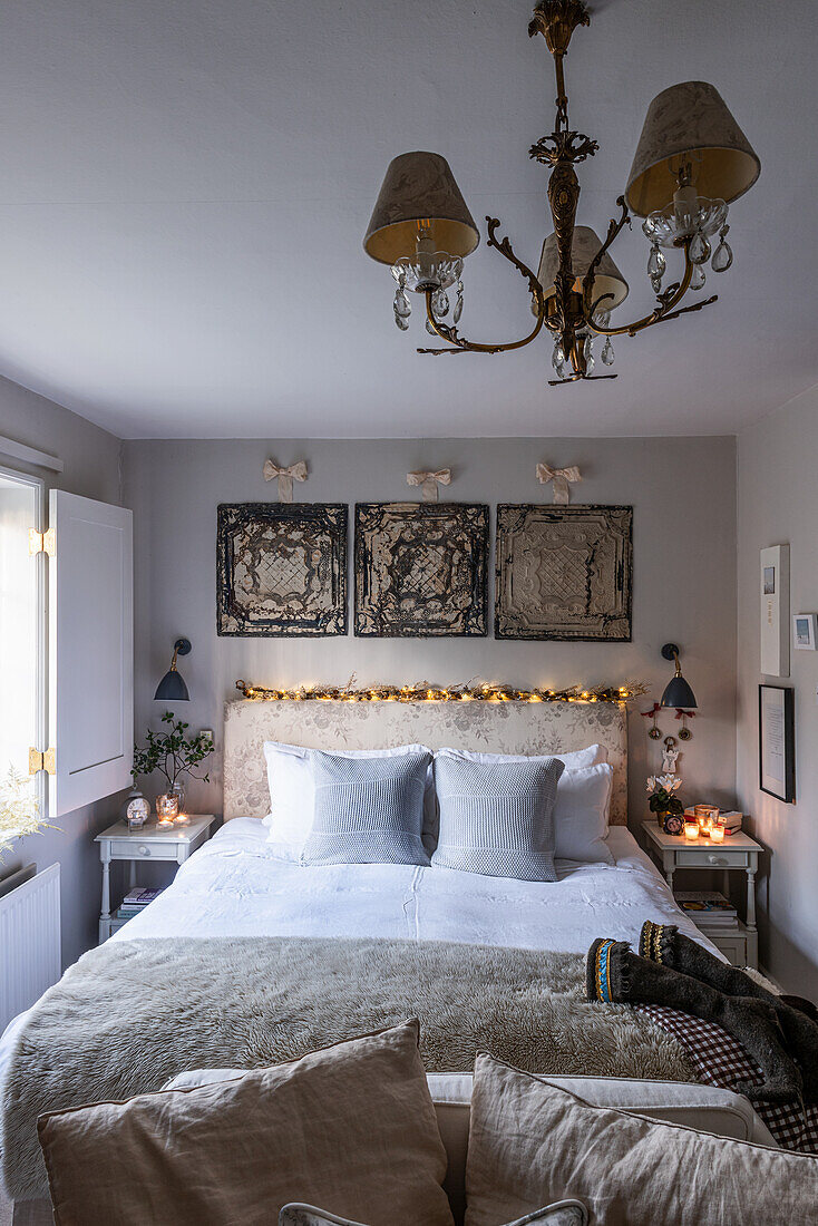 Double bed with Christmas decorations on headboard below vintage ornamental tiles in bedroom