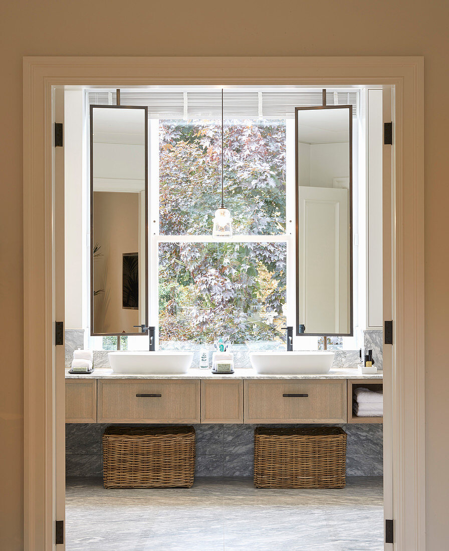 Zwei Waschbecken mit drehbaren Spiegeln vorm Fenster im Bad