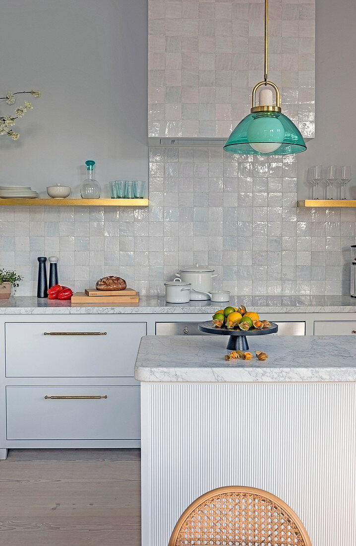 Kücheninsel mit Marmorplatte in weißer Küche mit glasierten Fliesen