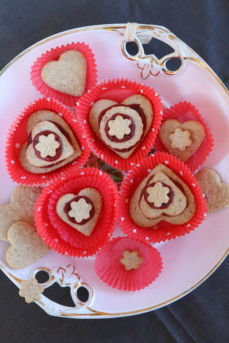 Heart-shaped biscuits with jam in red cake cases