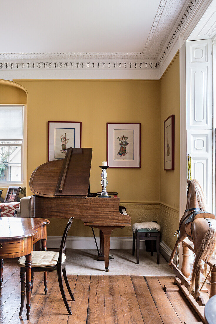 Baby grand piano in dining room with rocking horse and framed paintings of warriors