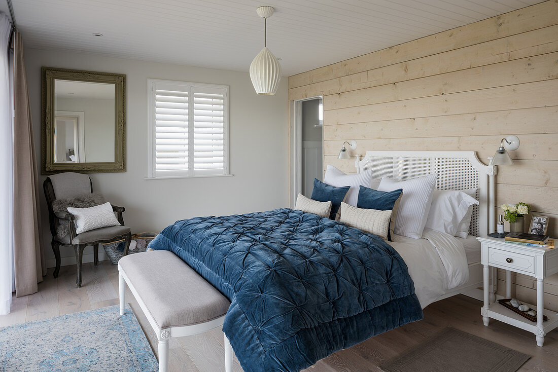 Blaue Steppdecke auf Doppelbett im Schlafzimmer mit Bretterwand