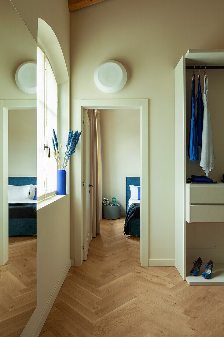 A walk-in wardrobe with view into a bedroom
