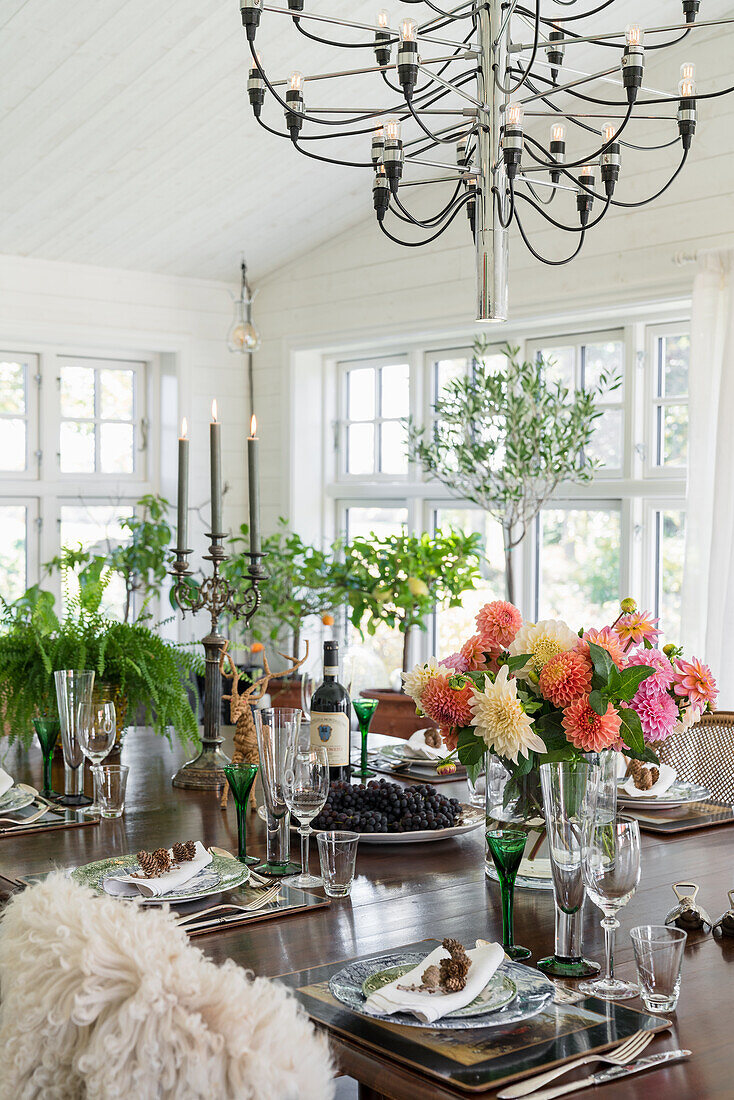 Dining table with bouquet of dahlias, chandelier above