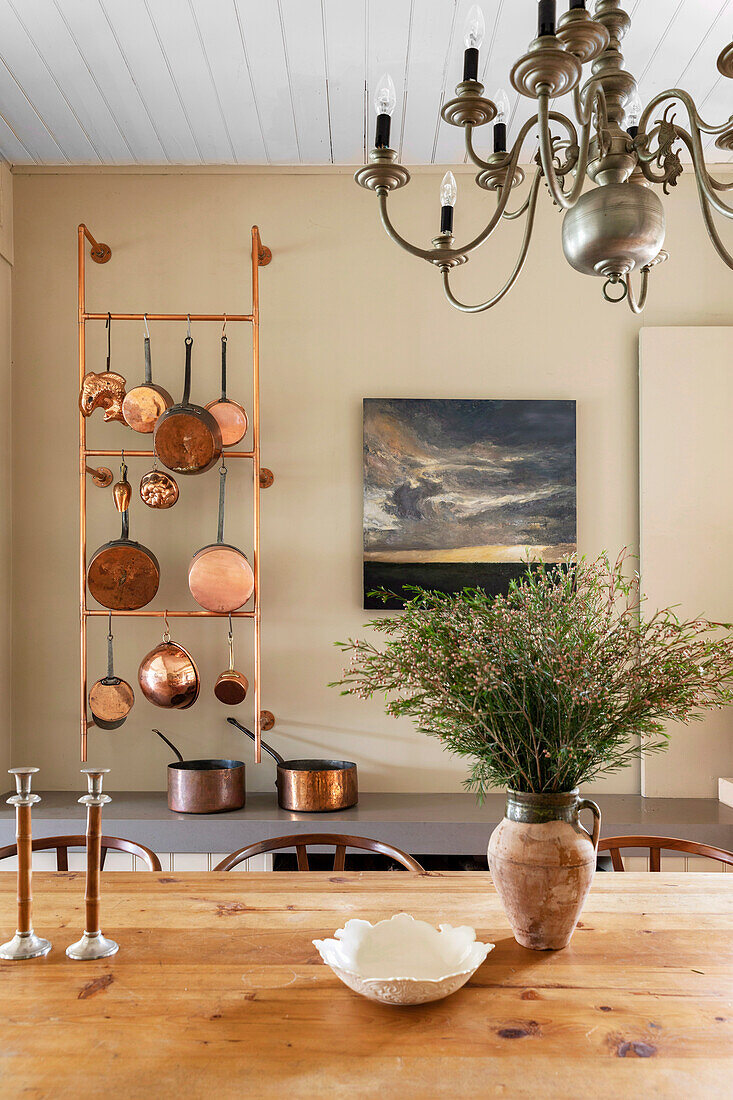 View over wooden table to vintage copper pans in a dining room