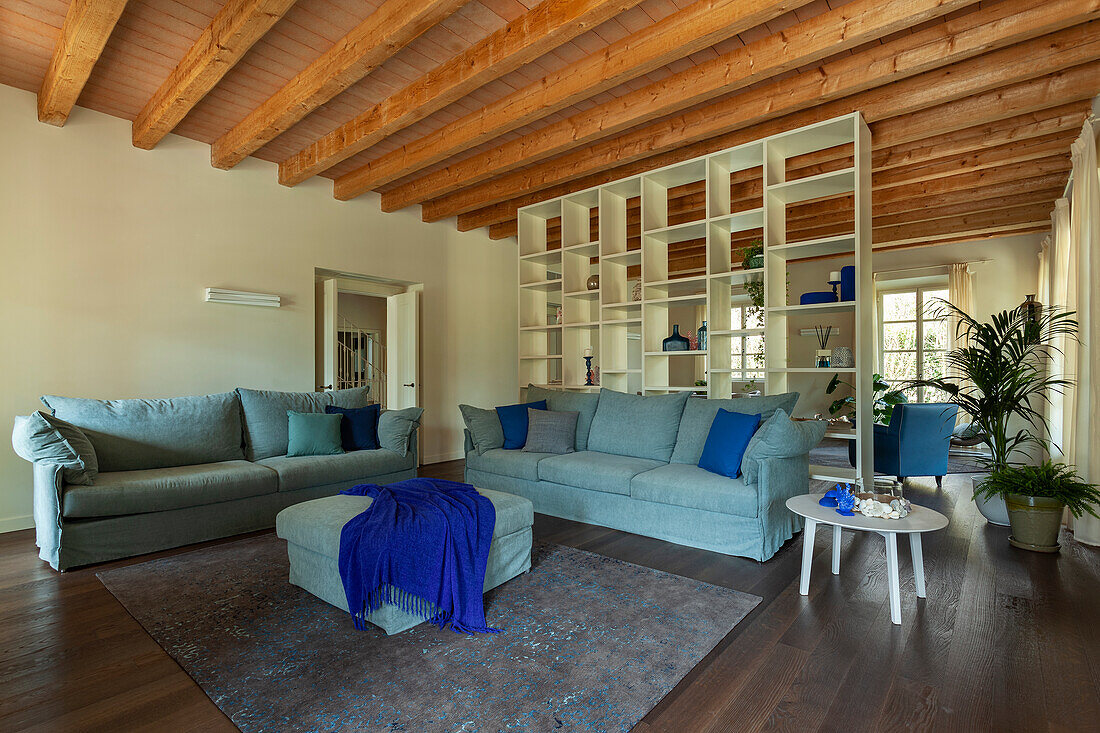 Lounge mit blauer Sofagarnitur und Holzdecke