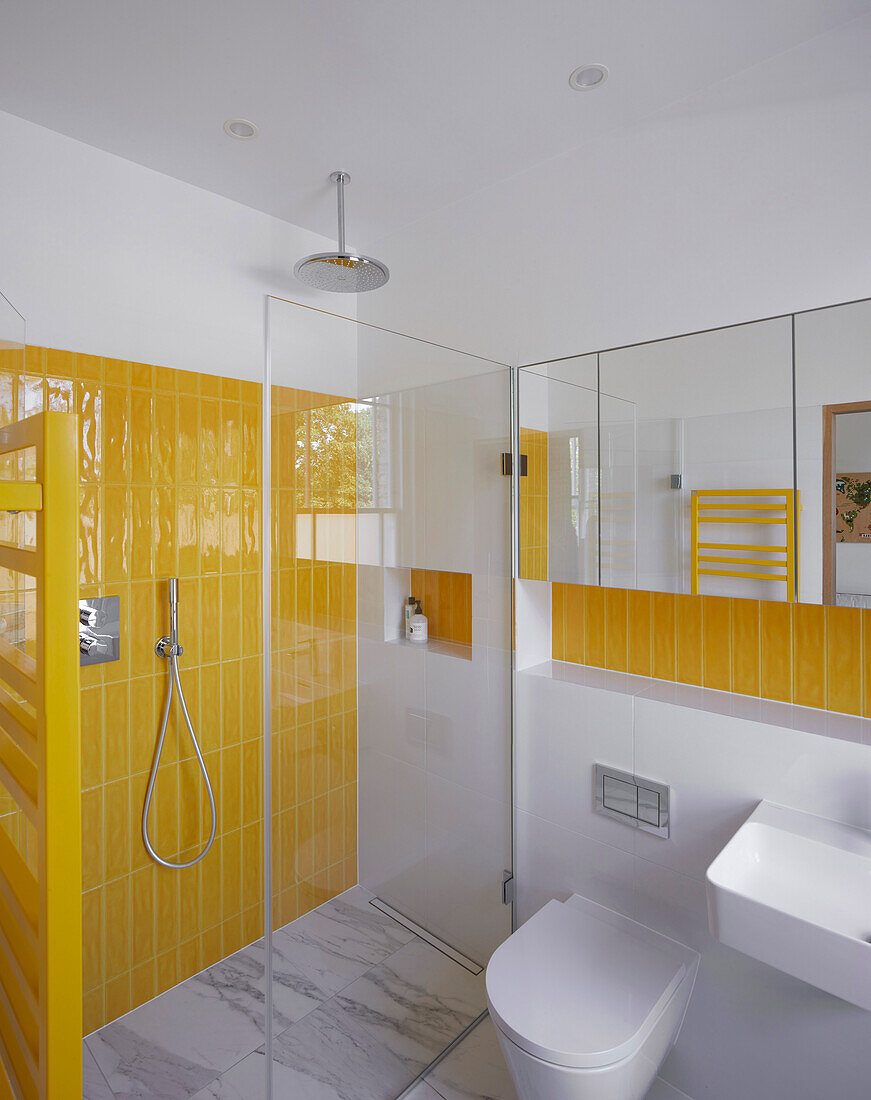 A shower area with yellow wall tiles in a bathroom
