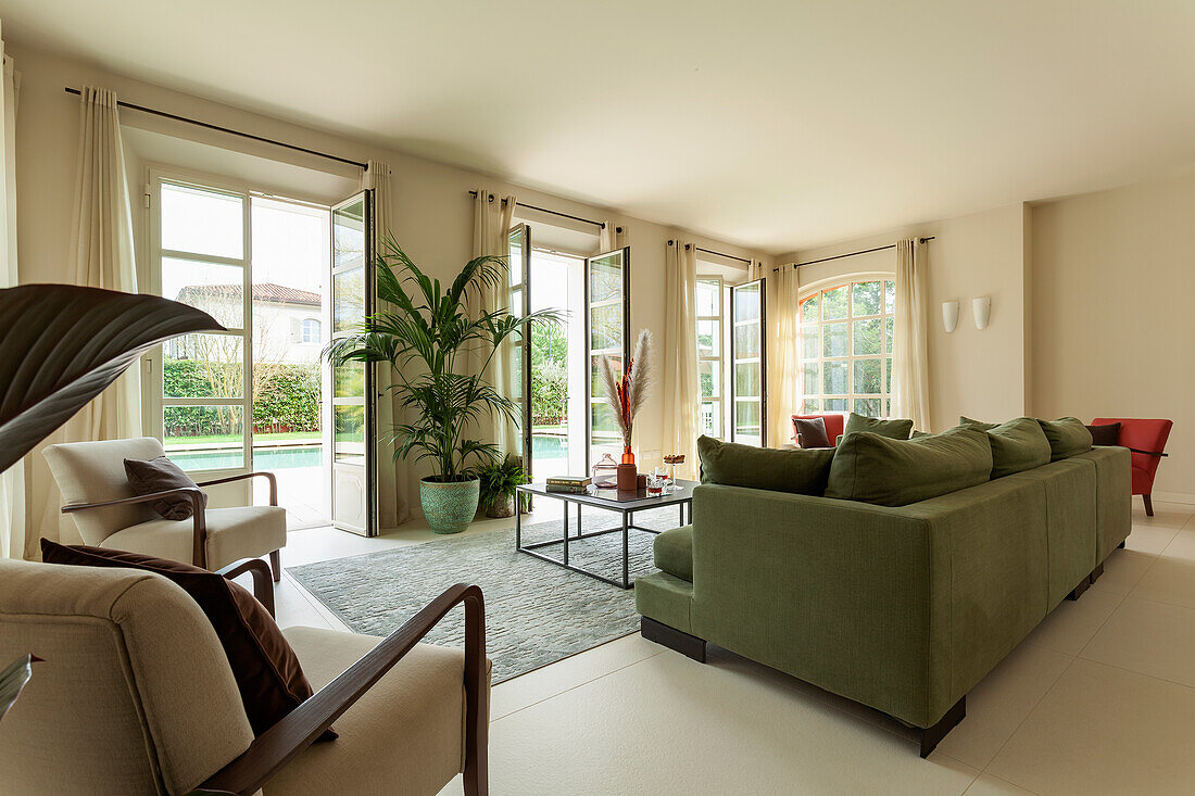 A green upholstered sofa in a lounge with open patio doors