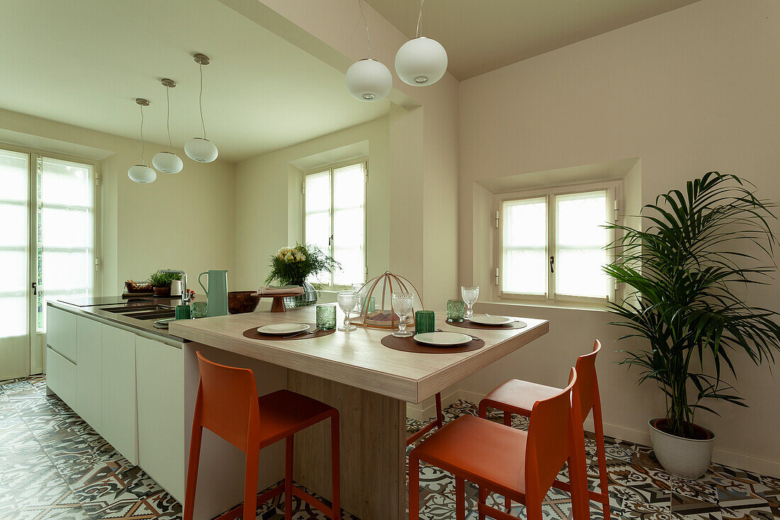 A kitchen counter with an adjacent breakfast table and red chairs