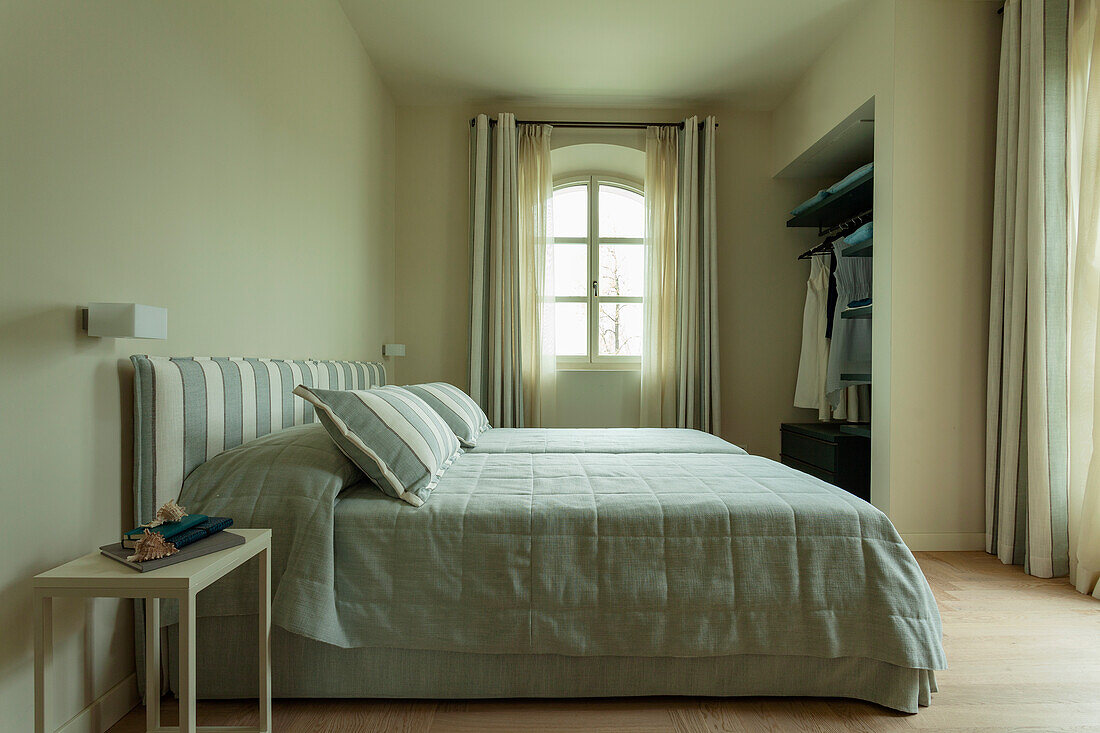 Bett mit mintgrüner Tagesdecke und farblich passendem Betthaupt im Schlafzimmer