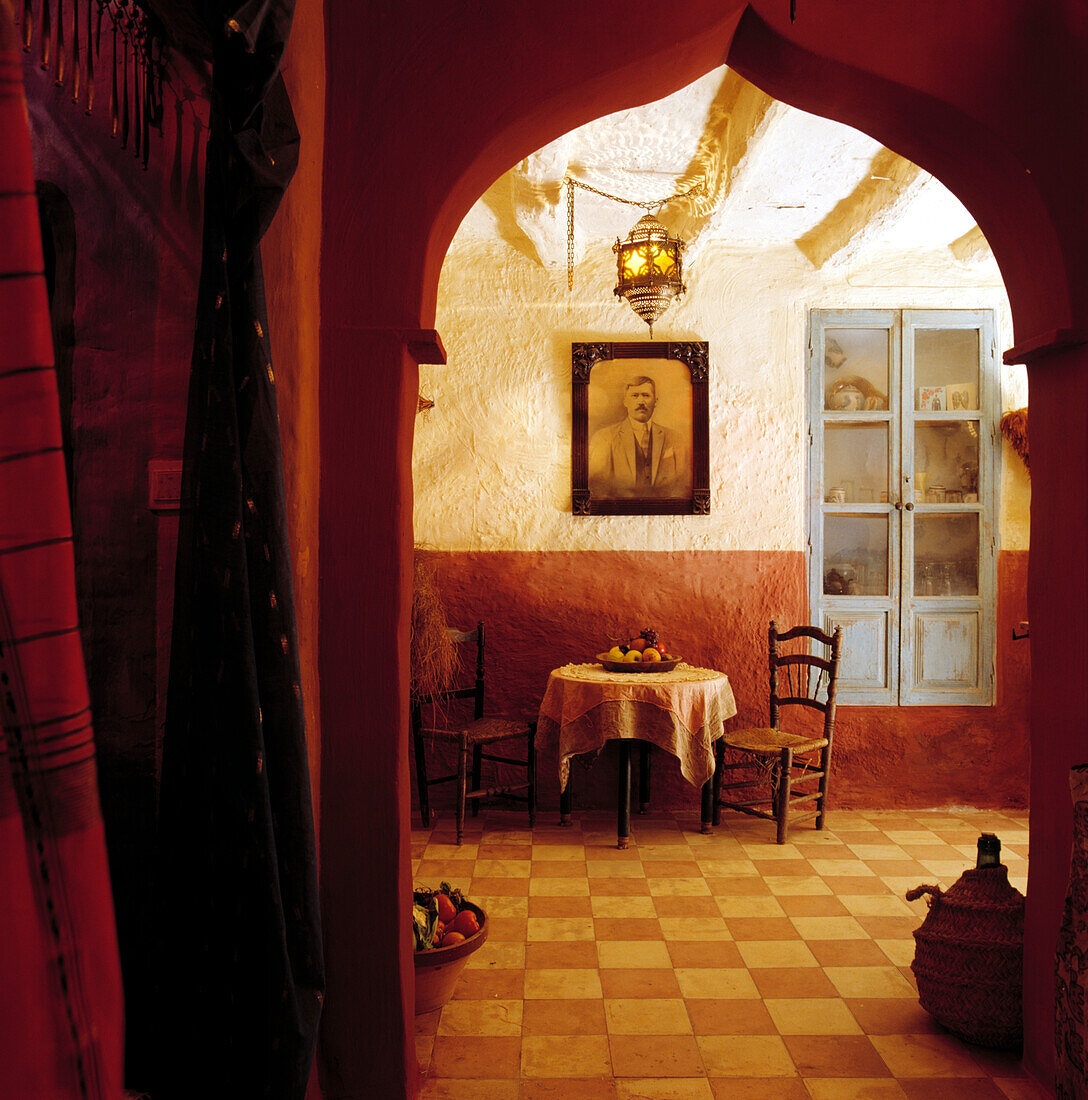 Terrakotta-Fliesenboden und maurischer Türrahmen im rustikalen Speisesaal mit blau verglasten Türen am Alkovenschrank