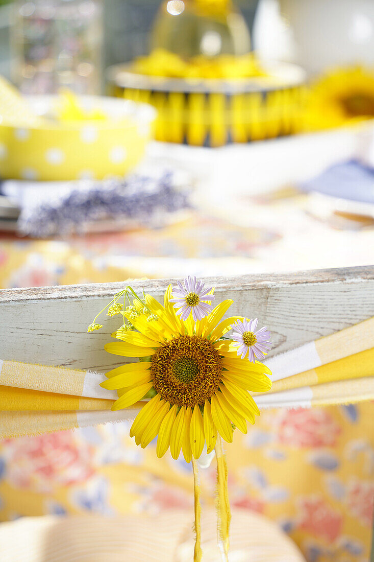 Stuhldeko mit Sonnenblumenblüte und gelb kariertem Band