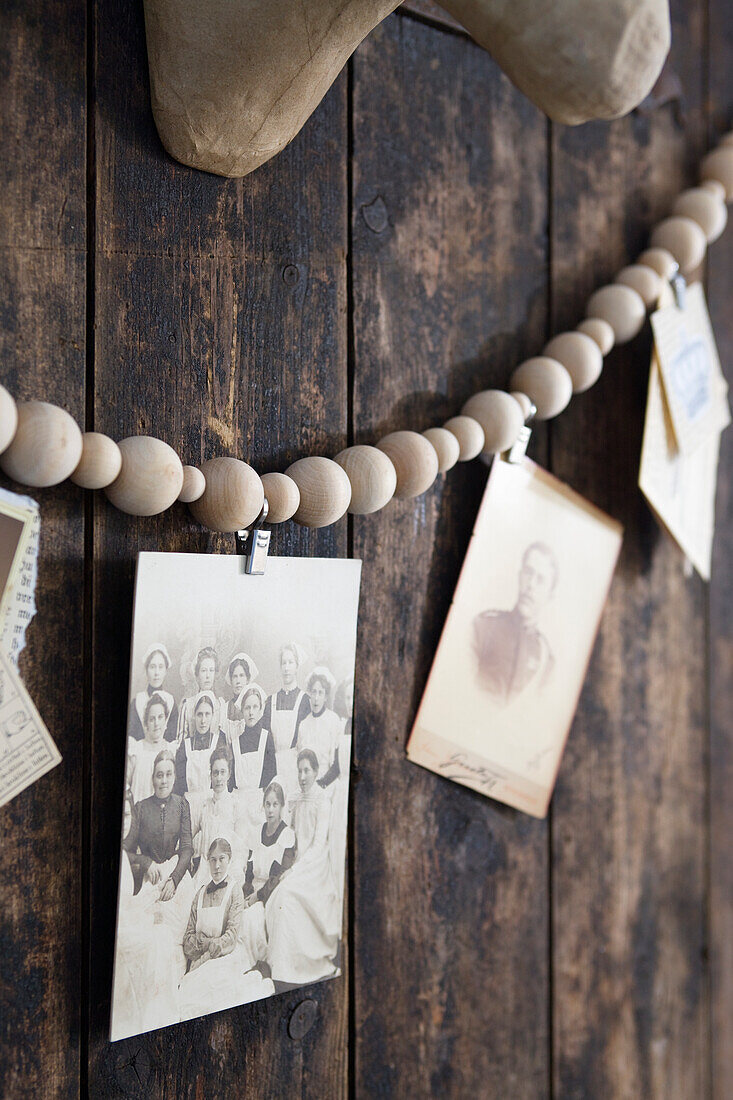 DIY-Girlande aus Holzkugeln mit Vintage Fotos an Holzwand
